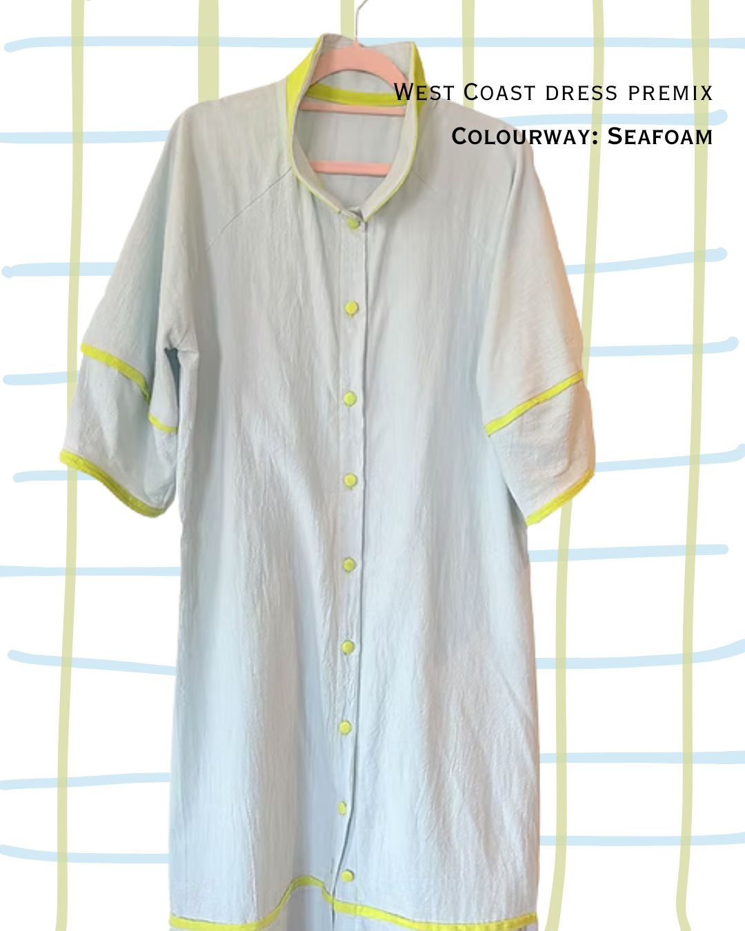Light blue cotton dress with yellow accents on a hanger against a striped background