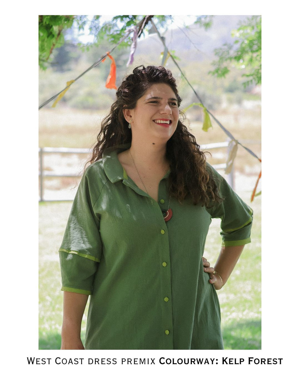 Woman wearing a green dress standing outdoors with trees and bunting in the background