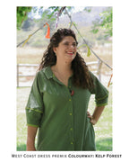 Woman wearing a green dress standing outdoors with trees and bunting in the background