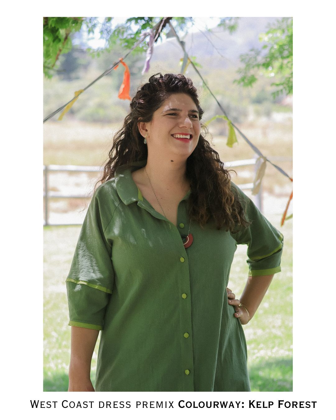 Woman wearing a green dress standing outdoors with trees and bunting in the background