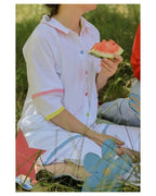 Person eating watermelon outdoors with a colorful dress.